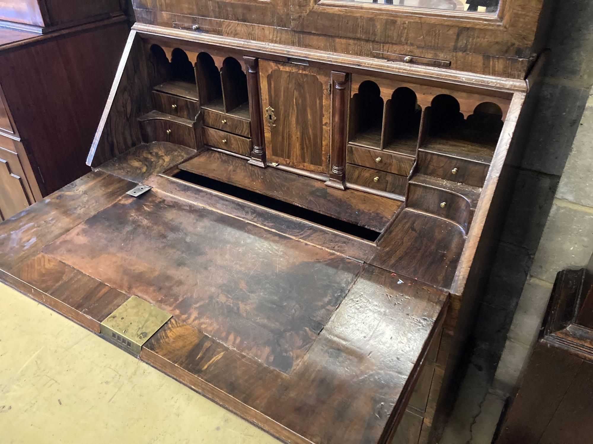 A mid 18th century style walnut bureau bookcase, with two mirrored doors enclosing a single adjustable shelf over candle slides and fal